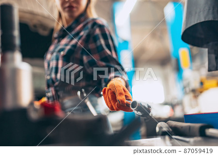 Female auto mechanic. beautiful young red-headed girl in working process at auto service station, indoors. Gender equality. Work, occupation, fashion, job Female auto mechanic. beautiful young red-headed girl in working process at auto service station, indoors. Gender equality. Work, occupation, fashion, job 87059419