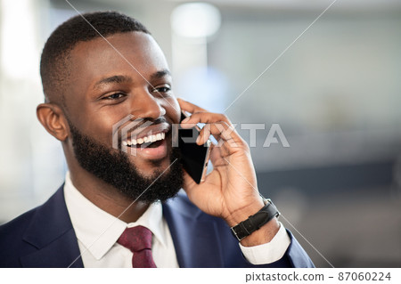 Happy handsome black businessman talking on phone, busienss center interior 87060224