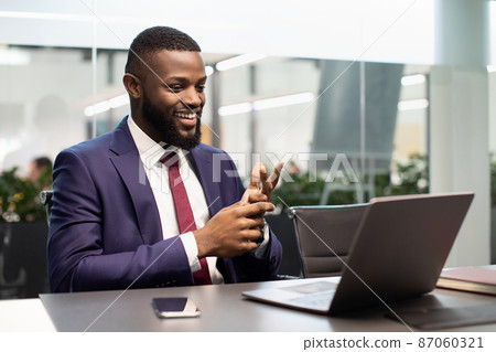 Handsome black businessman having video chat, using laptop Handsome black businessman having video chat, using laptop 87060321