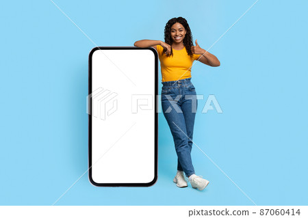 Positive african american lady posing with smartphone with blank screen 87060414