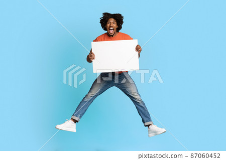 Emotional black guy jumping with empty placard over blue 87060452