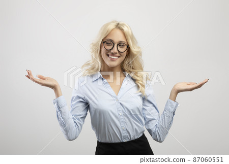 Positive woman in formal wear comparing options, making scales with her hands, holding invisible objects Positive woman in formal wear comparing options, making scales with her hands, holding invisible objects 87060551
