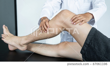 Female physiotherapist doing healing treatment and rehabilitation injured knee of patient by stretching 87061106