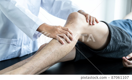 Female physiotherapist doing healing treatment and rehabilitation injured knee of patient by stretching 87061107