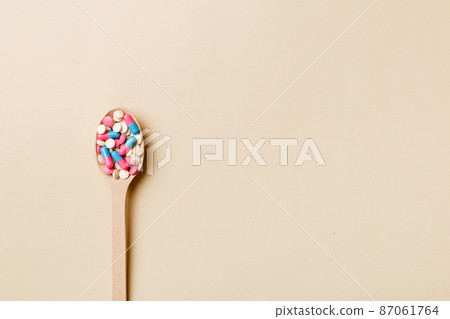 Vitamin capsules in a wooden spoon on a colored background. Pills served as a healthy meal. Drugs, pharmacy, medicine or medical healthycare concept Vitamin capsules in a wooden spoon on a colored background. Pills served as a healthy meal. Drugs, pharmacy, medicine or medical healthycare concept 87061764