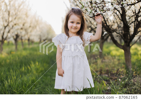 Adorable child posing at garden with blooming apple trees 87062165
