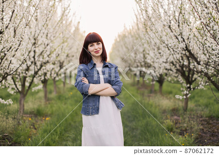 Stunning woman with crossed arms posing at blooming orchard 87062172