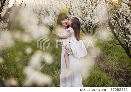 Female child kissing and embracing mother outdoors 87062211