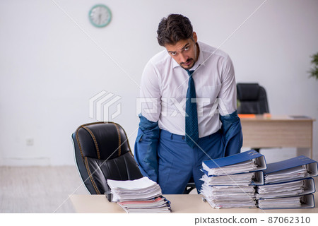 Young male employee and too much work in the office Young male employee and too much work in the office 87062310