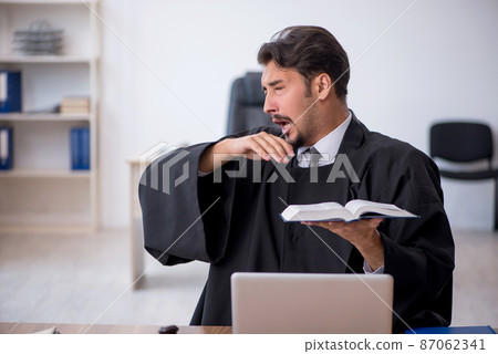 Young male judge reading book in the courthouse 87062341