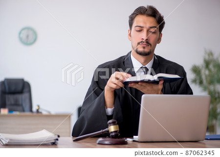 Young male judge reading book in the courthouse 87062345