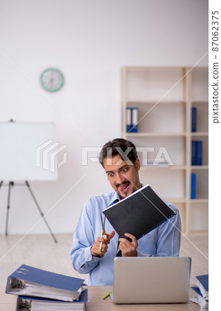 Young male employee unhappy with excessive work in the office Young male employee unhappy with excessive work in the office 87062375