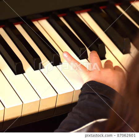 Girl's finger playing the piano 87062601
