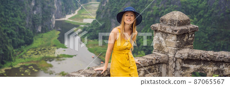 BANNER, LONG FORMAT Woman tourist on the lake Tam Coc, Ninh Binh, Viet nam. It's is UNESCO World Heritage Site, renowned for its boat cave tours. It's Halong Bay on land of Vietnam. Vietnam reopens 87065567