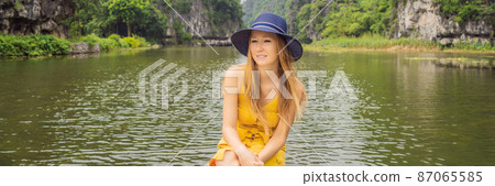 BANNER, LONG FORMAT Woman tourist in boat on the lake Tam Coc, Ninh Binh, Viet nam. It's is UNESCO World Heritage Site, renowned for its boat cave tours. It's Halong Bay on land of Vietnam. Vietnam 87065585