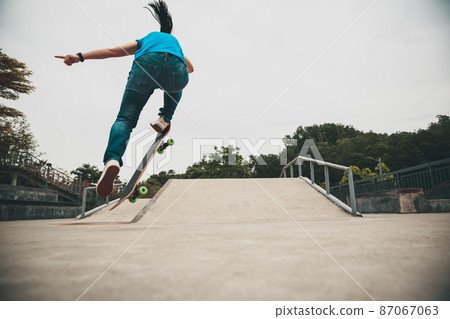Asian woman skateboarder skateboarding in modern city Asian woman skateboarder skateboarding in modern city 87067063