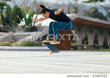 Asian woman skateboarder skateboarding in modern city 87067081