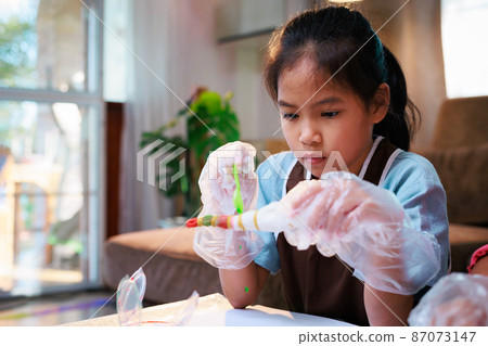 Asian child girl enjoy making tie dye cloth at home. Art and craft DIY for kid concept. Asian child girl enjoy making tie dye cloth at home. Art and craft DIY for kid concept. 87073147