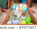 Asian siblings children are playing with baby bunny and decorating easter eggs preparing for Easter at home together with fun. Happy family Happy easter Happy holiday. 87073457