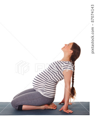 Pregnant woman doing yoga asana Ustrasana 87074143