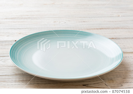 Perspective view of empty blue plate on wooden background. Empty space for your design 87074538