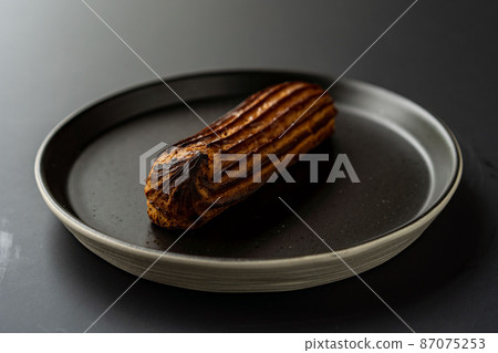 dessert is a small puff pastry pie with stuffing inside on a black serving plate on a black background . A piece of cake with a cut 87075253