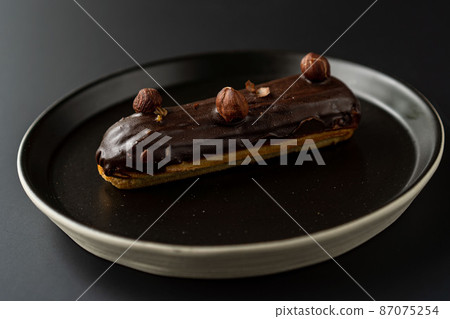 dessert is a small puff pastry pie with stuffing inside on a black serving plate on a black background . A piece of cake with a cut dessert is a small puff pastry pie with stuffing inside on a black serving plate on a black background . A piece of cake with a cut 87075254