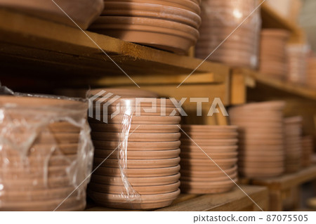 Clay plates for flower pots in stretch film on shelves in store 87075505