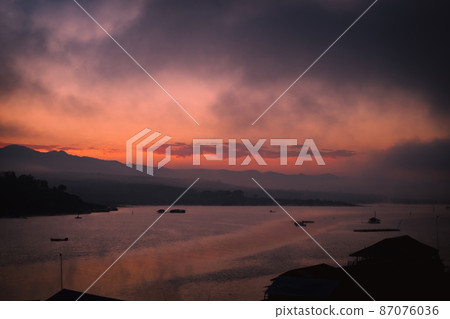 Scenery of sunrise over beautiful lake with warm sky and sunlight reflected water ripple on a winter morning. 87076036