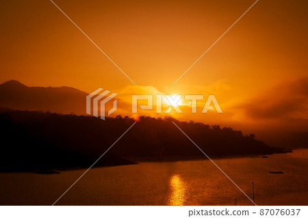 Beautiful sunrise over the lake with warm skies and sparkling reflections on the water surface. 87076037