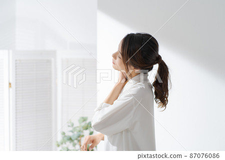 Profile of a woman touching her neck 87076086