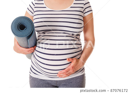Pregnant woman standing with yoga mat Pregnant woman standing with yoga mat 87076172