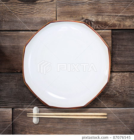 Plates and chopsticks placed on a wooden table 87076545