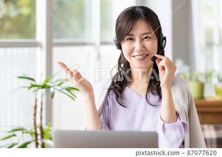 一位在室內戴耳機並前往筆記本電腦的女商人 87077620