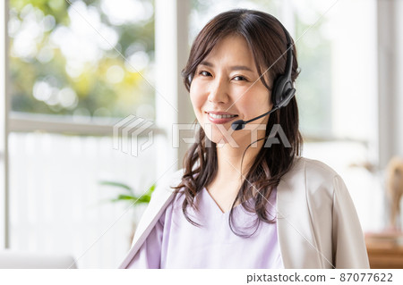 一位在室內戴耳機並前往筆記本電腦的女商人 87077622