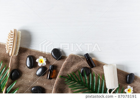 Organic spa products for massage with essential oil and black zen stones top view on white wooden background. 87078191