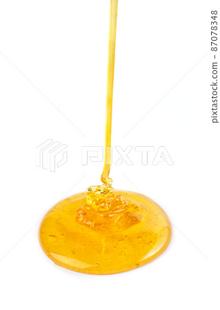 Pouring honey isolated on white background. Honey or caramel drop. 87078348