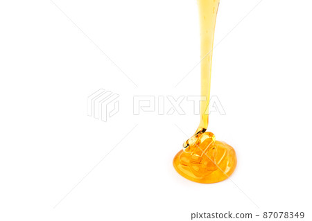 Pouring honey isolated on white background. Honey or caramel drop. 87078349