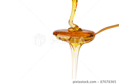 Honey dripping on spoon isolated on white background. Organic honey drop. Honey dripping on spoon isolated on white background. Organic honey drop. 87078365