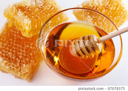 Sweet honey and honeycomb. Healthy organic honey in a bowl and wooden honey dipper. Sweet healthy dessert. 87078375