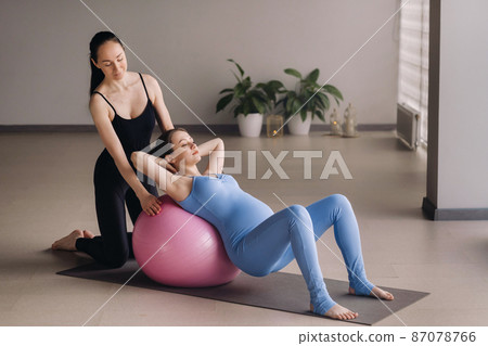 Pregnant woman with a trainer during fitness classes with a ball Pregnant woman with a trainer during fitness classes with a ball 87078766