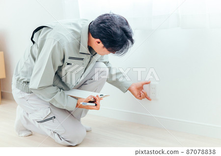 A man in work clothes checking an outlet 87078838
