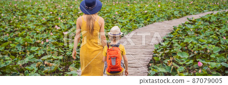 BANNER, LONG FORMAT Mother and son in a yellow on the path among the lotus lake. Mua Cave, Ninh Binh, Vietnam. Vietnam reopens after quarantine Coronovirus COVID 19 concept 87079005