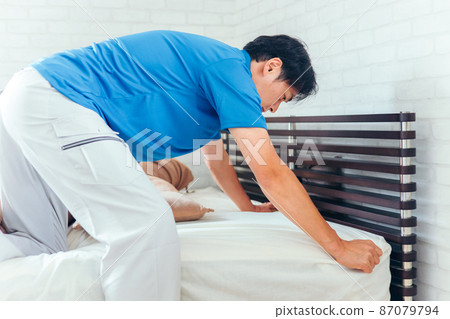 Men in work clothes making beds and cleaning rooms 87079794