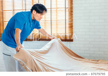 Men in work clothes making beds and cleaning rooms 87079795