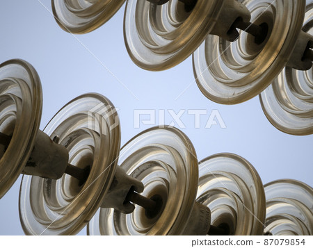 High Voltage electric wires cap and pin insulator detail on blue sky High Voltage electric wires cap and pin insulator detail on blue sky 87079854