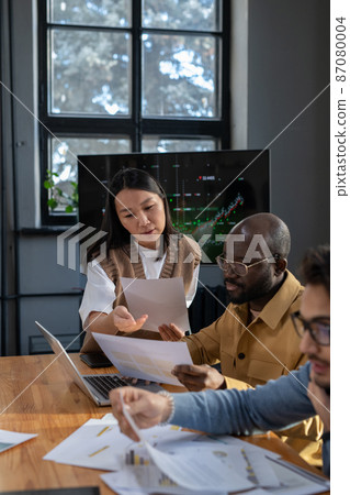 Young confident Asian businesswoman with paper consulting male colleague Young confident Asian businesswoman with paper consulting male colleague 87080004