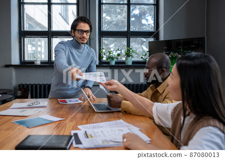 Young confident speaker passing document to colleague before presentation Young confident speaker passing document to colleague before presentation 87080013