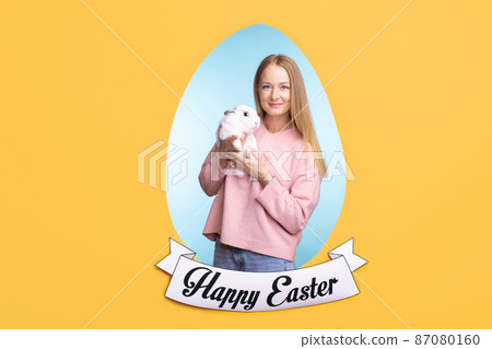 Happy young beautiful female in pink sweater holding Easter bunny Happy young beautiful female in pink sweater holding Easter bunny 87080160