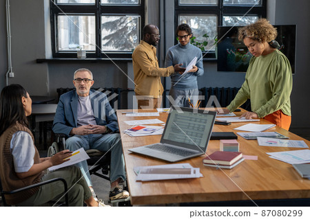 Several colleagues discussing working points and looking through papers 87080299